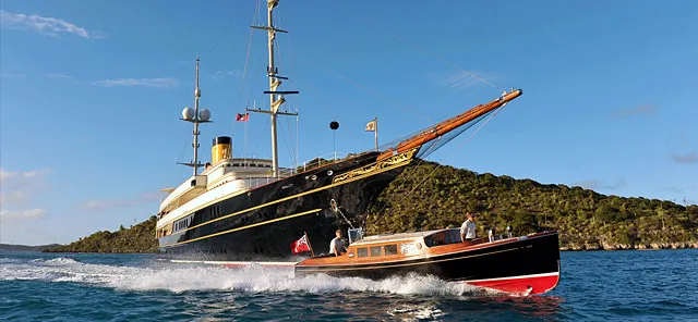 Tender racing alongside classic yacht